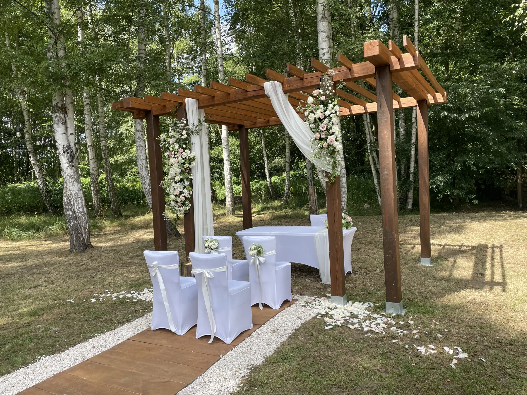 Drewniana altana i białe krzesła przygotowane na ceremonię w lesie